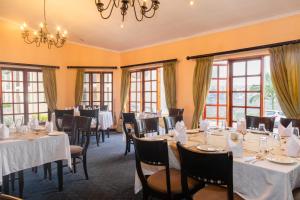 a dining room with tables and chairs and windows at Malawi Sun Hotel & Conference Centre in Blantyre