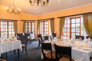 un comedor con mesas, sillas y ventanas en Malawi Sun Hotel en Blantyre