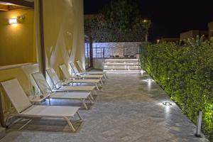 - une rangée de chaises blanches sur une terrasse la nuit dans l'établissement B&B Aloe Comfort Rooms, à San Vito Lo Capo