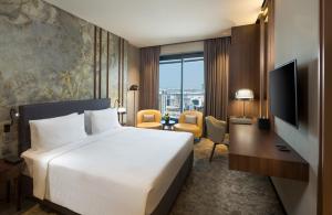 a hotel room with a bed and a desk and a television at Millennium Place Barsha Heights Hotel in Dubai