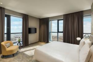 a hotel room with a bed and a chair and windows at Millennium Place Barsha Heights Hotel in Dubai