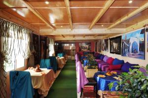 a dining room with tables and purple and blue couches at Maison d'hôtes Jnan Atlas in Sidi Abdalwahad