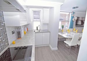a white kitchen with a table and a dining room at Twenty Three B - 3 bedroomed apartment in Lee-on-the-Solent
