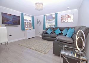 a living room with a brown couch and blue pillows at Twenty Three B - 3 bedroomed apartment in Lee-on-the-Solent