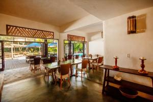 a dining room with tables and chairs and windows at Pousada Farol das Tartarugas in Praia do Forte