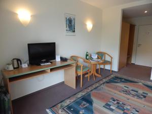 Habitación con escritorio, TV y mesa con sillas. en Hotel garni Am Brunnenplatz, en Gerolstein
