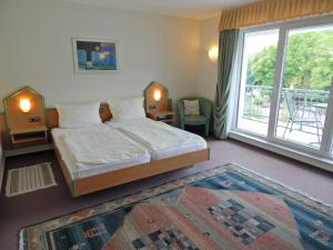 a bedroom with a bed and a large window at Hotel garni Am Brunnenplatz in Gerolstein