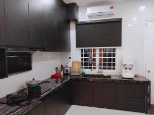 a kitchen with black cabinets and a black counter top at Sea Lion Kuala Selangor Semi-Detached Homestay in Kuala Selangor