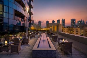 a rooftop patio with tables and chairs on a building at Millennium Place Barsha Heights Hotel in Dubai