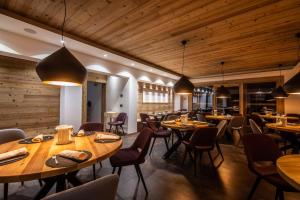 サント・ステーファノ・ディ・カドーレにあるMonaco Sport Hotelの木製の天井、テーブルと椅子のあるレストラン