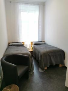 twee bedden in een kamer met een stoel en een raam bij FEWO am Neuen Dom in Linz