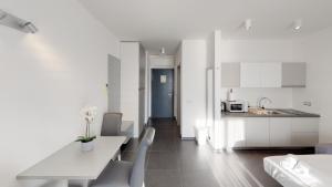 cocina con armarios blancos, mesa y sillas en Whitehouse Apartments, en Makarska