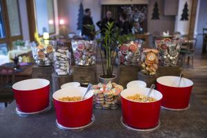 une table avec des bols rouges de nourriture et des vases dans l'établissement Hôtel de La Vanoise, à Pralognan-la-Vanoise