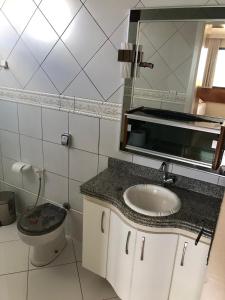 a bathroom with a sink and a toilet and a mirror at Apartamento amplo, arejado e confortável - Mínimo 3 noites in Ilhéus +25 photos
