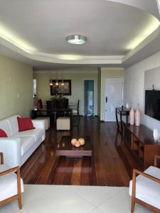a living room with a white couch and a table at Apartamento amplo, arejado e confortável - Mínimo 3 noites in Ilhéus
