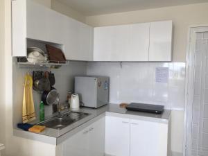 una cocina blanca con fregadero y armarios blancos en JACY Apartment - Phan Rang, Ninh Thuan en Phan Rang