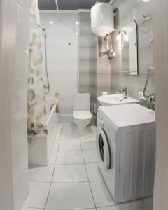 uma casa de banho com um lavatório e uma máquina de lavar roupa em Видовая квартира в новострое в центре Киева em Kiev