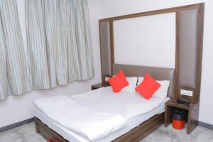 a bedroom with a bed with two red pillows at HOTEL SHIVAM in Howrah