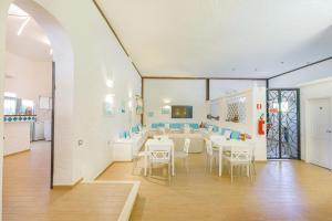 un comedor con mesas y sillas blancas en Hotel Mare Blue en Olbia