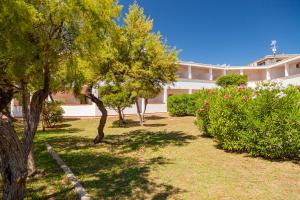a garden with trees and bushes in front of a building at Hotel Mare Blue in Olbia