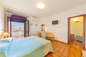 a bedroom with a bed and a table and a balcony at Hotel Mare Blue in Olbia