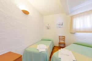 a room with two beds and a table and a chair at Hotel Mare Blue in Olbia