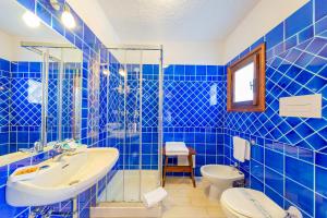a blue tiled bathroom with a sink and a toilet at Hotel Mare Blue in Olbia