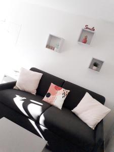 ein schwarzes Sofa mit Kissen im Wohnzimmer in der Unterkunft Studio rénové avec terrasse ST RAPHAEL in Saint-Raphaël