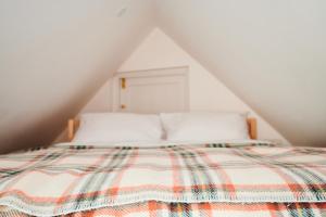 a bed with a checkered blanket on top of it at Tiny Cottage with Terrace & Parking, Central Lewes in Lewes