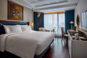 a hotel room with a large bed and a desk at Peridot Grand Luxury Boutique Hotel in Hanoi