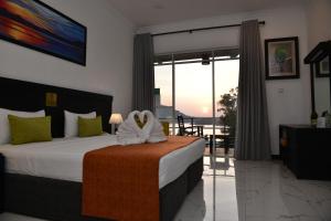 a bedroom with a bed with a view of a balcony at Agbo Hotel in Polonnaruwa