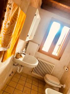 łazienka z umywalką, toaletą i oknem w obiekcie Casa Marcela w mieście Gravedona
