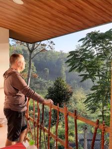 a man standing on a balcony looking out of a window at Ella Breeze Homestay in Ella