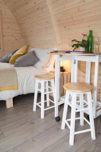 a bedroom with a bed and a desk and two stools at Clova pod, Kilry eco pods in Blairgowrie
