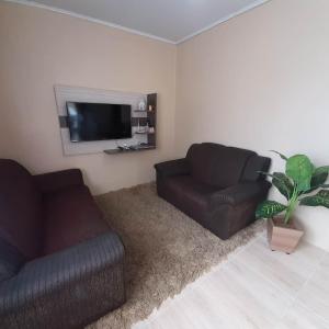 ein Wohnzimmer mit 2 Sofas und einem Flachbild-TV in der Unterkunft Casa da Cris/Marcelo in Gramado