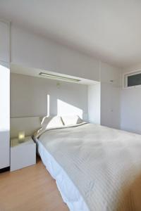 a white bedroom with a white bed and a window at Seascape in Ostend