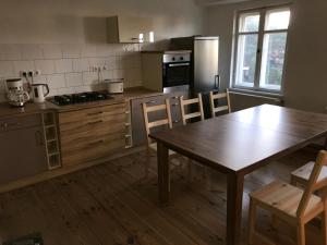 uma cozinha com uma mesa de madeira, uma mesa e cadeiras em Sanierte möblierte Altbauwohnung am Waldrand für bis zu 6 Personen em Borkheide