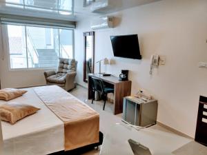 a bedroom with a bed and a desk and a tv at APARTAHOTEL LION in Tuluá