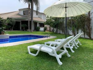 two white lounge chairs and an umbrella next to a pool at Cespedes House Rooms in Lima