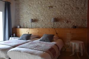 2 Betten in einem Schlafzimmer mit einer Steinmauer in der Unterkunft Le Tilleul de Ray in Ray-sur-Saône