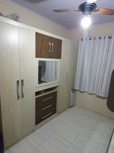 a living room with a ceiling fan and a kitchen at Casas 2 Quadras do Mar in Itapema