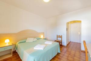 a bedroom with a bed and a desk with two towels at Hotel Mare Blue in Olbia
