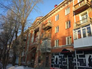 a red brick building with windows on a street at Apartment на Полковой в центре in Omsk