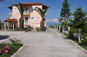 a driveway leading to a pink house with palm trees at Neptune Resort in Kavos