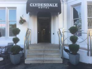 Clydesdale Hotel في هاميلتون: باب امام فندق فيه درج ونباتات