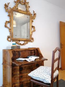 a mirror on top of a wooden dresser with a chair at Casa Palazzi in Venice