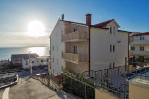 un edificio blanco con balcón junto al océano en Apartments Toni 2000, en Podstrana