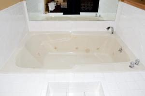y baño de azulejos blancos con bañera blanca. en Four Seasons Country Inn en Glasgow