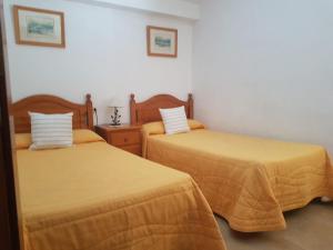 ロス・カンカホスにあるVivienda Vacacional la Palmeraの黄色いシーツが備わる客室内のベッド2台