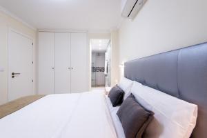 a bedroom with a large white bed with a blue headboard at Beach Front Apartment-1st Line in Marbella